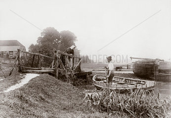 Man in a boat approaching woman on a bridge  c 1890s.