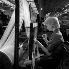 A woman draws a loom of glass and asbestos fabric  Dungannon  1963.