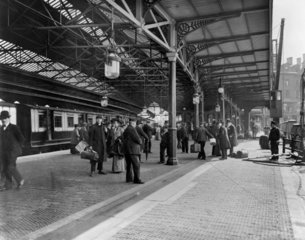 Railway travellers on a platform  c 1900s.