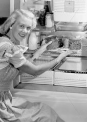 Woman taking food from a fridge  1950.