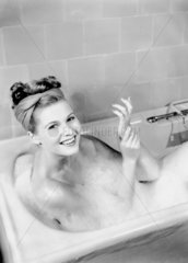 Woman lying in a foam bath  c 1950s.