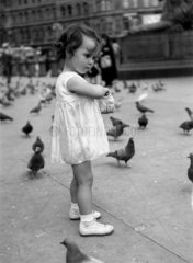 Little girl feeding the pigeons in Trafalgar Square  London  c 1930s.
