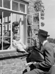 Man waving goodbye to a woman and baby  1951