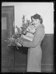 A young woman loaded with Christmas parcels  holly and mistletoe  1935.