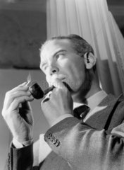 Man lighting a pipe  1950.
