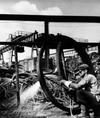 A scrap yard worker cuts a steel tyre with acetylene torch  1961.