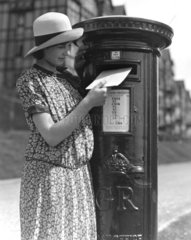 Young woman posting a letter  c 1930s.