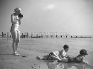 Woman in a bathing costume filming children