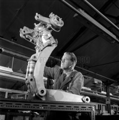 A worker at Dowty examines a hydraulic brace for a jet aircraft wheel assembly.