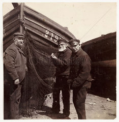 Fishermen standing by a net  c 1905.