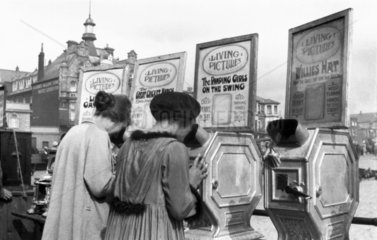 Two women peering into mutascopes  c 1930s.