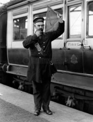 A guard waving his flag  Holyhead Station  c 1905.