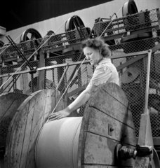 A young female worker leads electric cable on to a core at Britannic Cables.