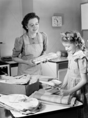 Mother and daughter sorting the laundry  1950.