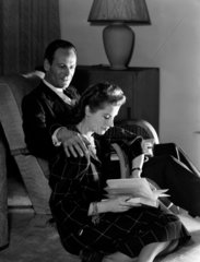 Man and woman reading by a fireside  1950.