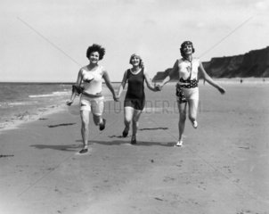 Women running along a beach  c 1920s.