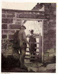 Two men talking over a gate  c 1905.