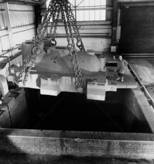A huge turbine casting is lowered by chains in to acid bath by worker  1967.