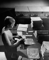 Littlewoods Pools: female worker sorts collected football coupons at desk  1970.