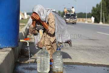 Nowshera  Pakistan  eine Frau holt am Strassenrand Wasser und waescht ihr Gesicht