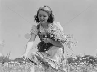 Young woman with an armful of daisies  c 1930s.