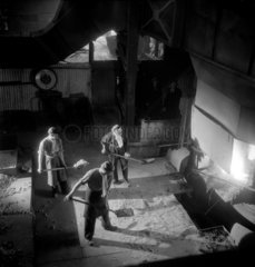 Three steel workers feeding a carbon arc furnace  Sheffield  1949.