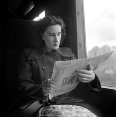 Woman reading a newspaper in a train carriage  1950.