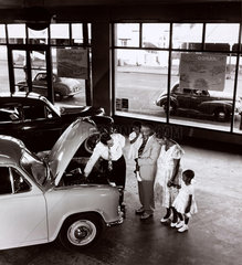 A Guyanian family are shown a Morris car in showroom  1958.