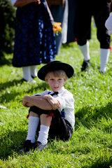 Sankt Maergen  Deutschland  ein Junge in traditioneller Tracht sitzt im Gras