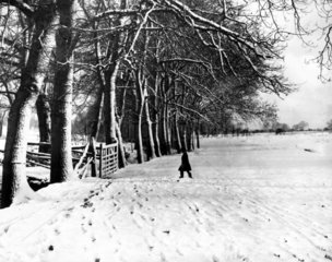 A schoolboy walking through the snow in a p