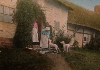 Women with dogs outside a cottage  c 1910-1915.