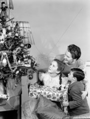 Woman and two children looking at a Christmas tree  c 1948.