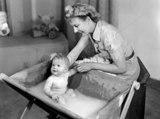 Woman bathing a baby  1948.