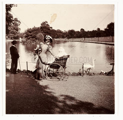 Woman and wheelchair in a park  c 1900.