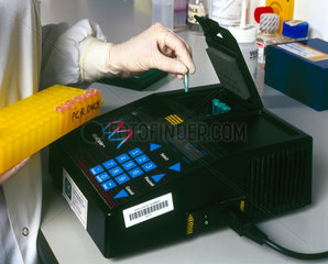 Molecular geneticist loading a thermal cycler.