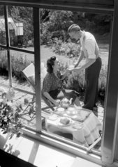 Couple taking afternoon tea in the garden  1951.