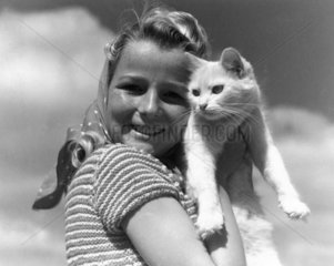 Girl posing for camera with a white cat  c
