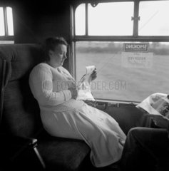 Woman reading a newspaper during her journey  1950.
