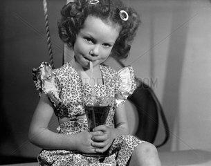 Little girl drinking juice through a straw  1950.