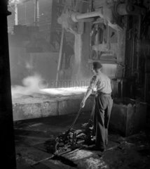 Steelworker at forge tending a rolled steel plate  Consett Iron Company  1957.