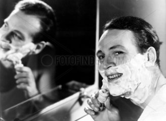 Man applying shaving foam to his face  c 1950s.