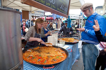 London  Grossbritannien  eine junge Marktfrau verkauft an ihrem Marktstand Paella