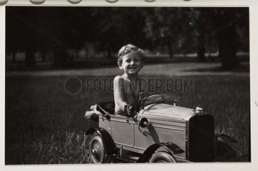 Boy driving a toy pedal car  c 1930.