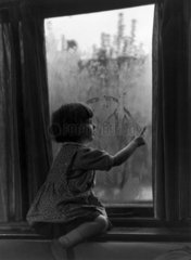 Girl drawing on a window  c 1920s.