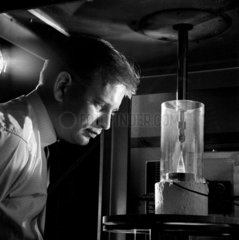A chemist examines zinc tungstate crystal growing in laboratory at Mullard.