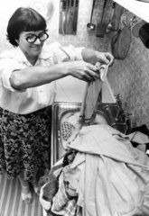 Woman washing clothes in a sink  c 1980s.