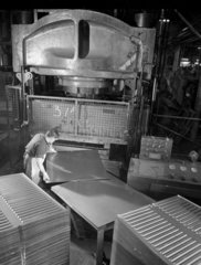 Worker pushes blank sheets into press to form radiators  Newcastle Upon Tyne.