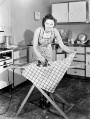 Woman ironing in the kitchen  late 1940s.