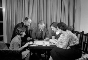 A family playing a game of Monopoly  c 1930.