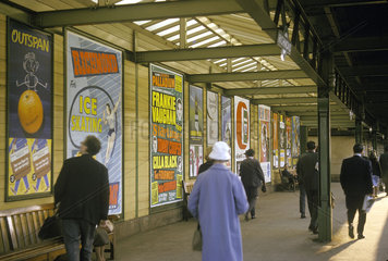 Passengers and poster advertisements on railway platform  London  1965.